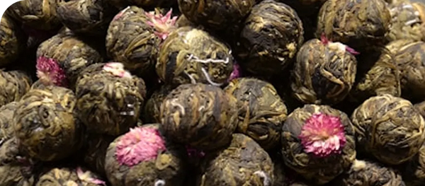Close-up of tea balls with pink flowers on a dark background